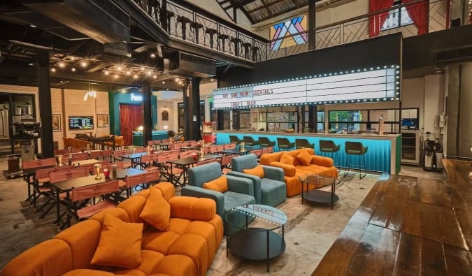 Tables and comfy chairs set up in front of a stage at a cinema bar at the Prince Theatre Heritage Stay hotel in Bangkok, Thailand