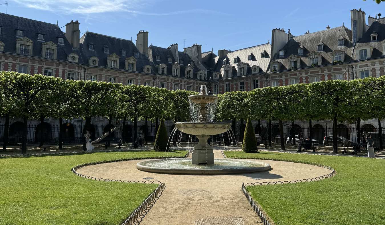 Place des Vosges, a grassy square with a fountain in the middle in the neighborhood of Le Marais in Paris, France