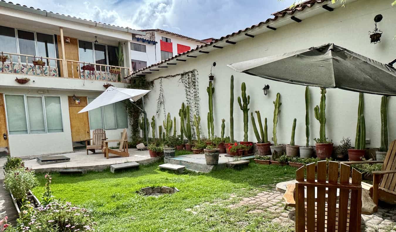 A vibrant mural on the wall next to wooden dorm beds with red curtains at Viajero Kokopelli, a hostel in Cusco, Peru